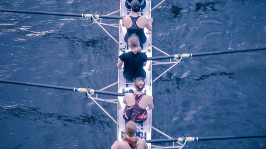 Equipe féminine faisant de l'aviron pour illustrer l'article sur Ancrer l'apprentissage dans la réalité : un changement de comportement durable pour les équipes réelles