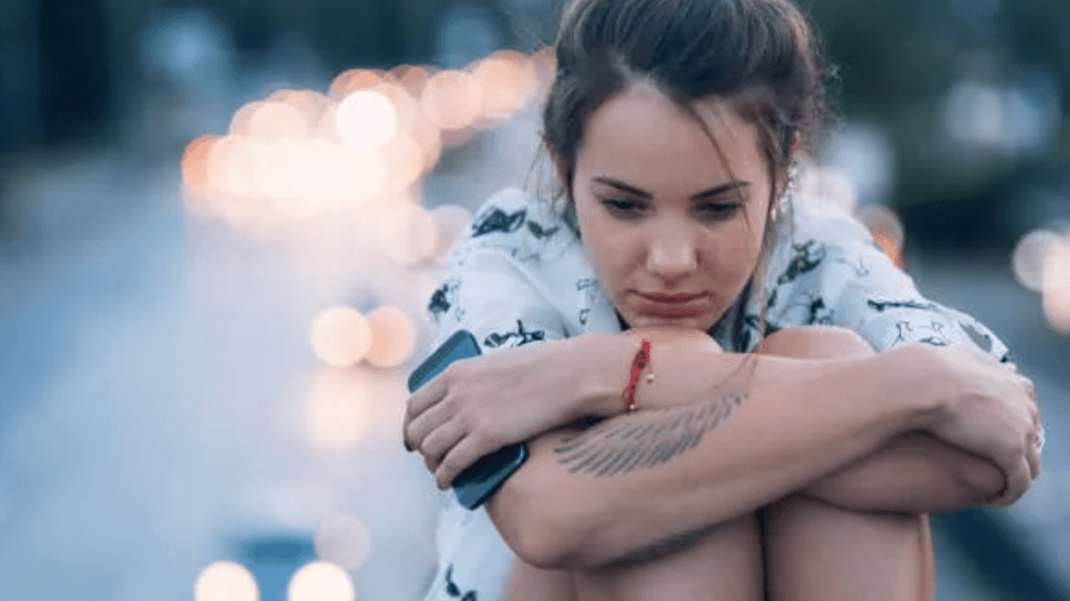 femme assise jambes dans les bras perdus dans ses pensées pour illuster Comment Belbin peut aider à répondre aux quatre facteurs du désengagement des employés